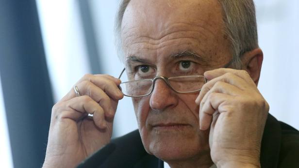 Ein älterer Mann hält seine Brille vor sein Gesicht.