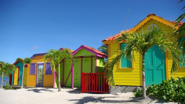 Eine Reihe von bunten Strandhäusern unter einem strahlend blauen Himmel.