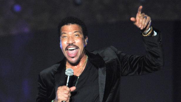 Lionel Richie singt mit erhobenem Zeigefinger auf einem Konzert.