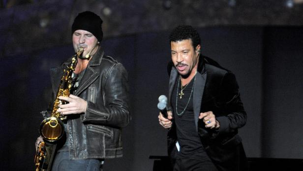 Lionel Richie tritt mit einem Saxophonisten auf einer Bühne auf.