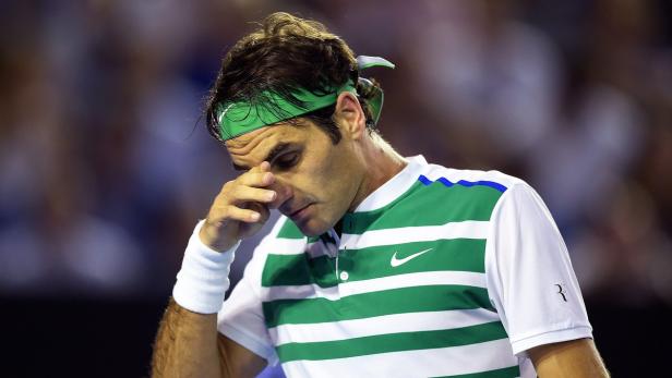 Roger Federer mit einem grünen Stirnband wischt sich den Schweiß von der Stirn.