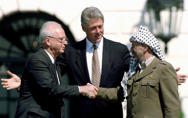 Bill Clinton, Jitzchak Rabin und Jassir Arafat schütteln sich die Hände.