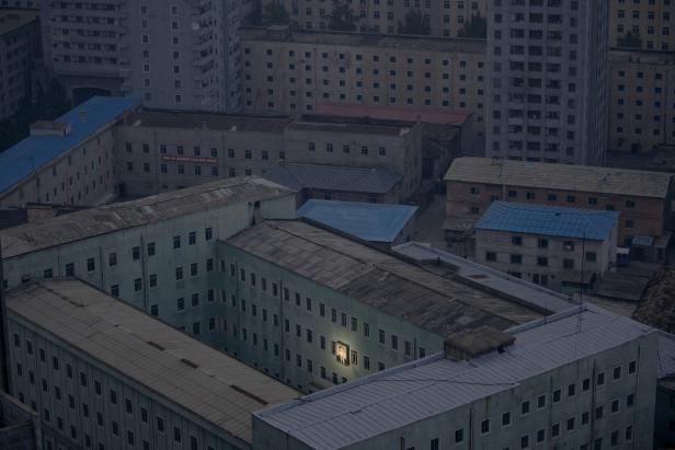 Luftaufnahme von einem Gebäude in Nordkorea mit einem beleuchteten Porträt von Kim Il-sung.