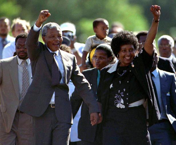Nelson Mandela und eine Frau mit erhobenen Fäusten bei einer öffentlichen Veranstaltung.