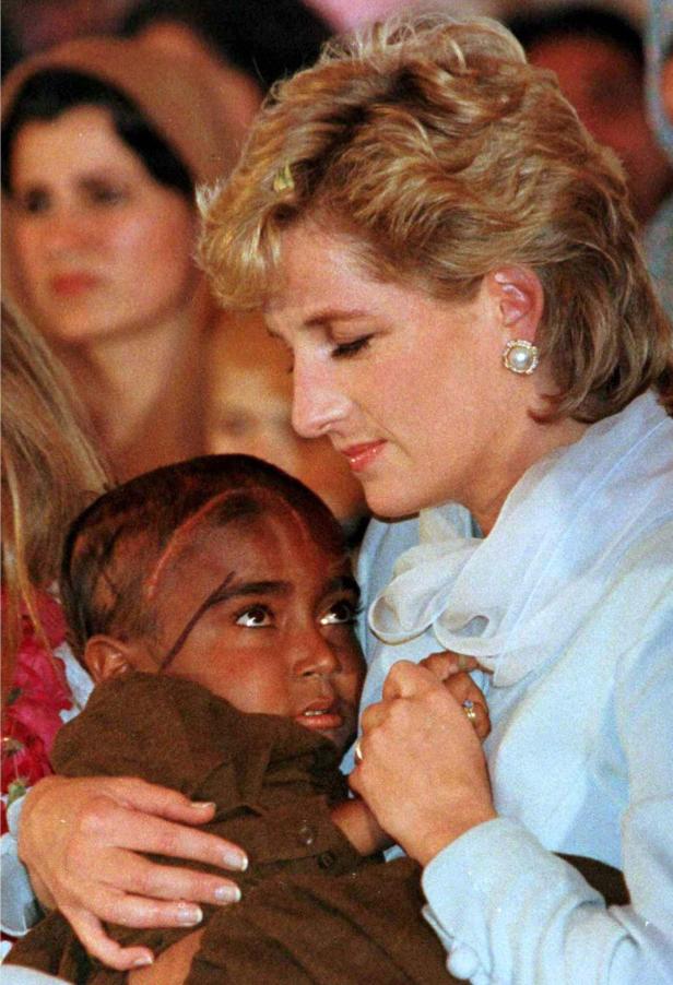 Diana, Prinzessin von Wales, umarmt ein Kind.