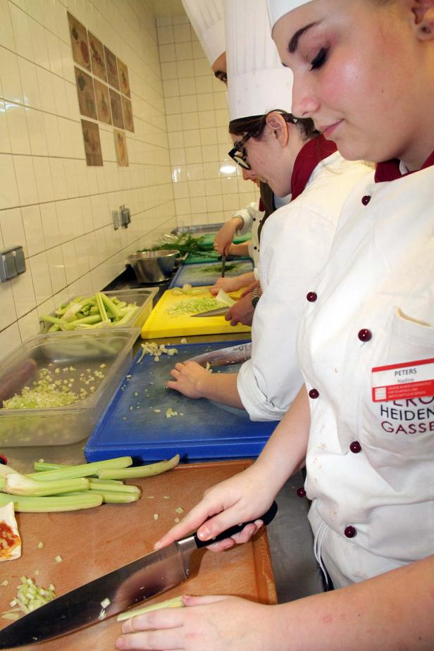 Köche bereiten in einer Küche Gemüse vor.