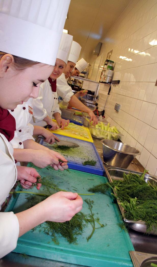 Köche bereiten in einer Küche Dill und Gemüse zu.