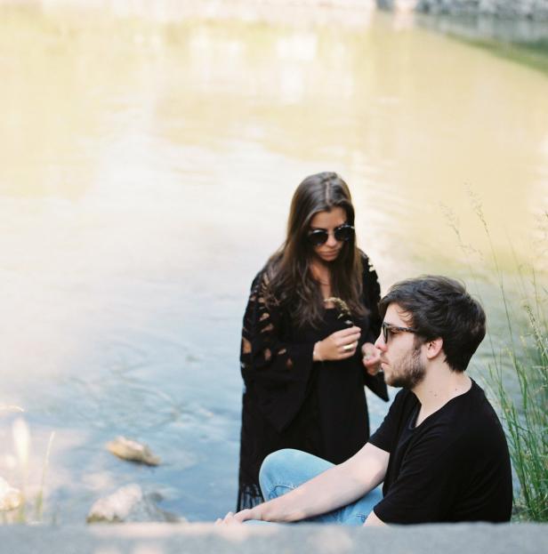 Ein Paar mit Sonnenbrillen sitzt am Ufer eines Sees.