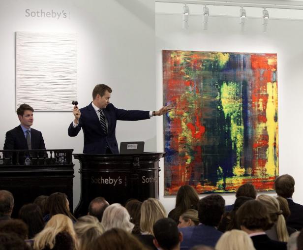 Ein Auktionator von Sotheby's präsentiert ein Gemälde vor einem Publikum.