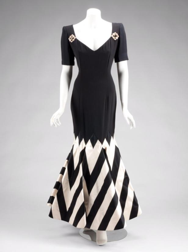 Ein schwarzes Abendkleid mit V-Ausschnitt und einem Rock mit schwarzen und weißen Streifen.