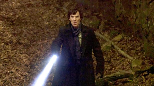 Benedict Cumberbatch als Sherlock Holmes mit einer Taschenlampe in einem dunklen Wald.