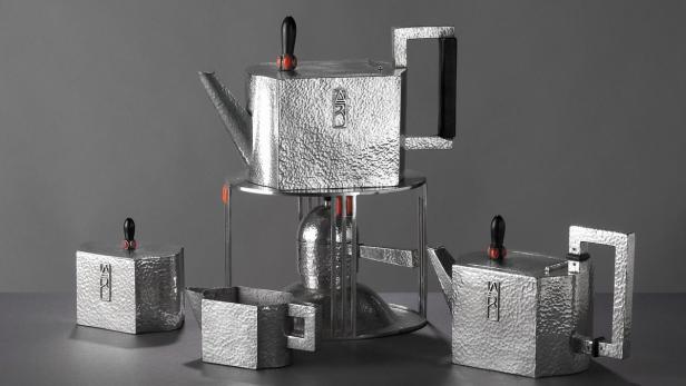 Ein Teeservice aus gehämmertem Silber mit geometrischen Formen steht auf einem Tisch.