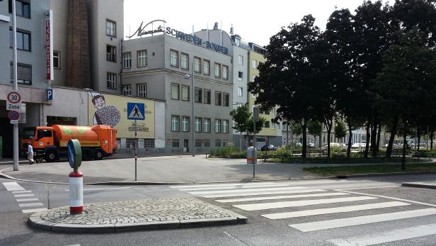 Eine Straßenkreuzung in Wien mit einem Gebäude, das mit „Schwedebomben“ beschriftet ist.