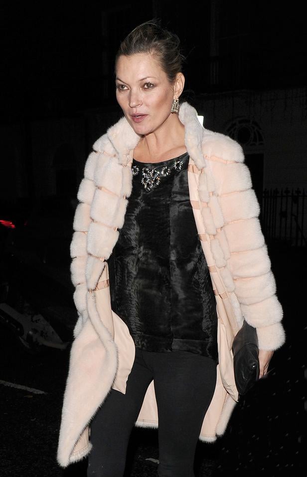 Kate Moss trägt einen hellrosa Pelzmantel und eine schwarze Hose.