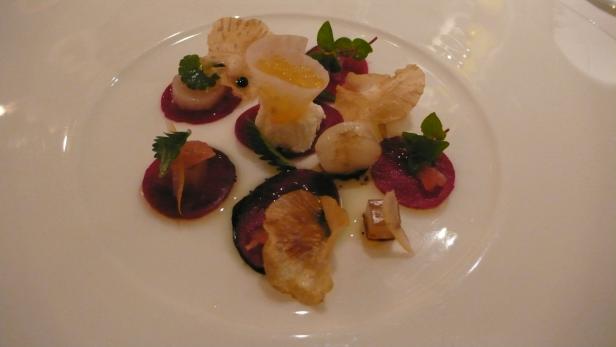 Ein Teller mit kunstvoll angerichteten Vorspeisen, darunter Rote Bete und Jakobsmuscheln.