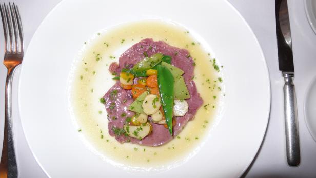 Ein Teller mit Vitello Tonnato und Gemüse in heller Sauce.