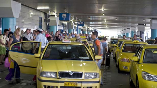Eine Schlange von gelben Taxis wartet vor einem Flughafenterminal auf Fahrgäste.