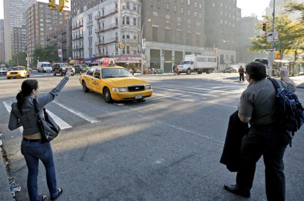 Eine Frau und ein Mann versuchen, in einer belebten Straße in New York ein Taxi zu rufen.