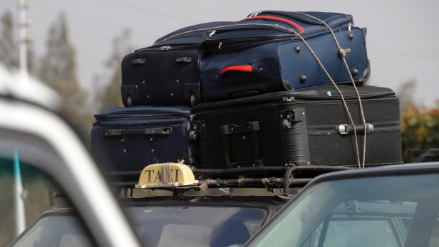 Mehrere Koffer sind mit einem Seil auf dem Dach eines Taxis befestigt.
