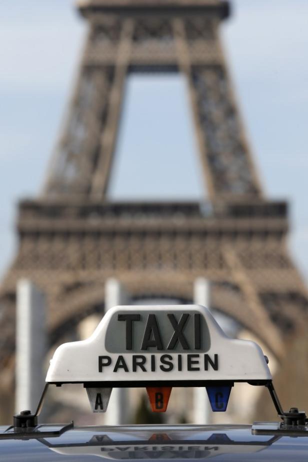Das Schild eines Pariser Taxis vor dem Eiffelturm.
