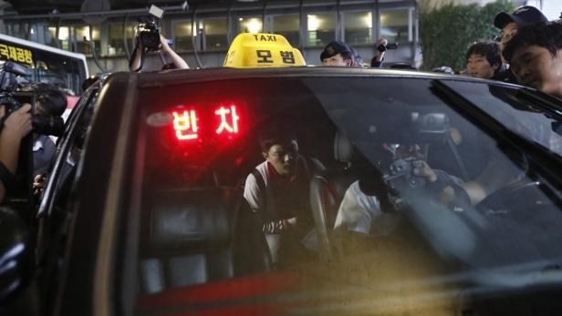 Ein Mann sitzt in einem Taxi, umringt von Fotografen.