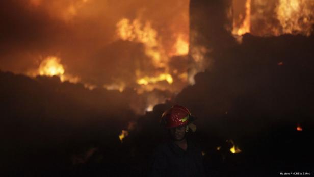 Ein Feuerwehrmann steht vor einem großen Brand.