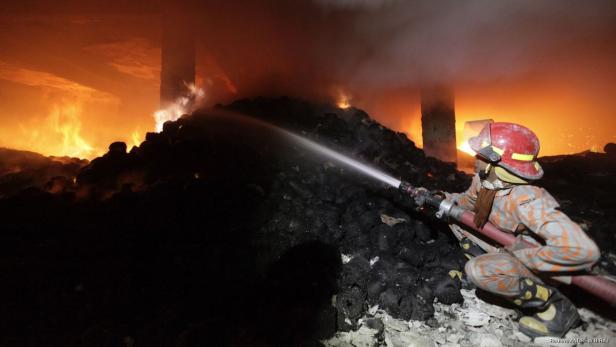 Ein Feuerwehrmann bekämpft einen Brand mit einem Wasserstrahl.
