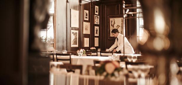Ein Kellner deckt in einem eleganten Restaurant einen Tisch ein.