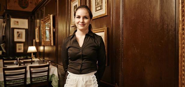 Eine Kellnerin in einer Gaststätte mit dunkler Holzvertäfelung.