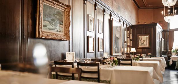 Ein elegant gedeckter Tisch in einem klassischen Restaurant mit dunkler Holzvertäfelung und Kunstwerken.