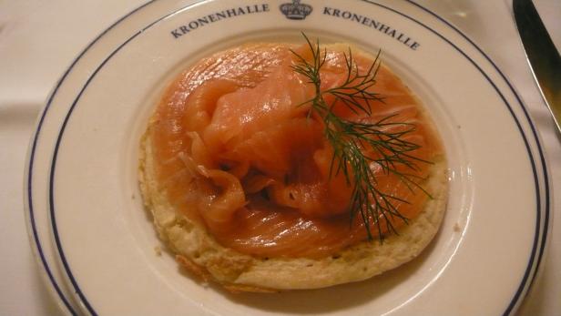 Ein Teller mit einem Brötchen belegt mit Lachs und Dill im Restaurant Kronenhalle.