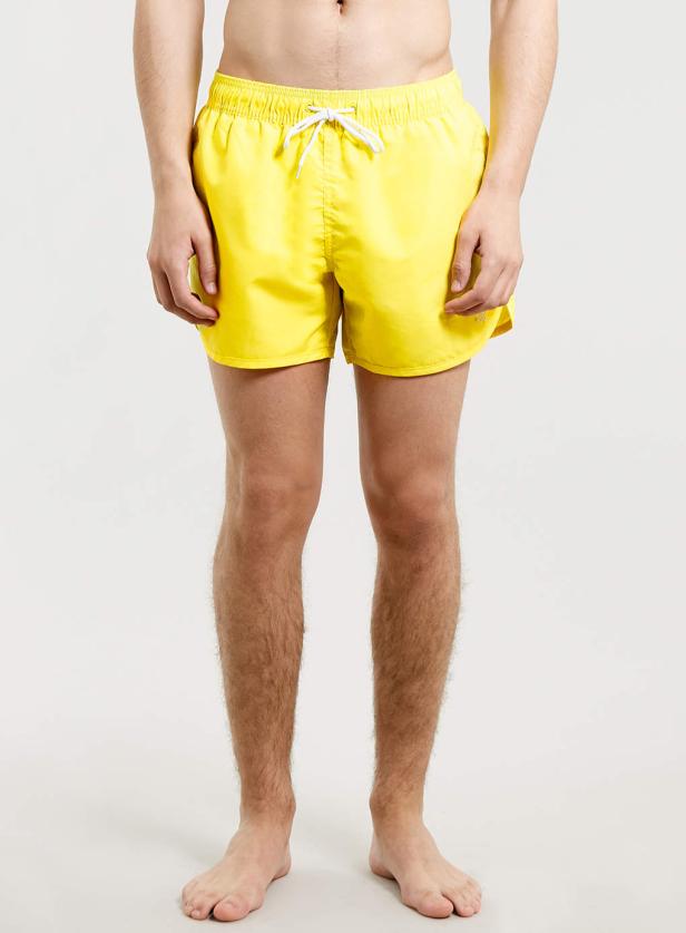 Ein Mann trägt eine gelbe Badehose mit weißen Kordeln.