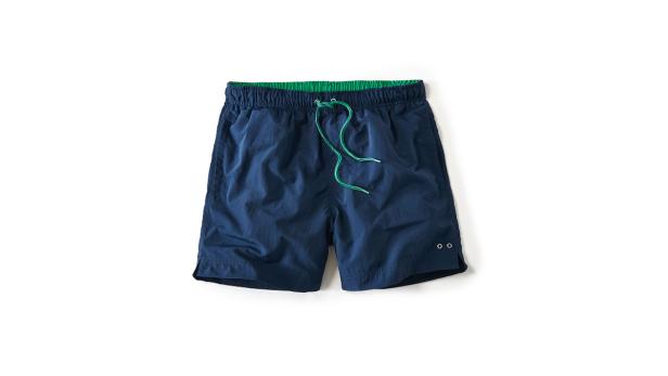 Eine blaue Badeshorts mit grünem Bund liegt auf einem weißen Hintergrund.