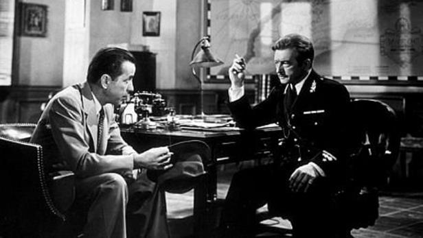 Ein Mann im Anzug spricht mit einem Polizisten in einem Büro.