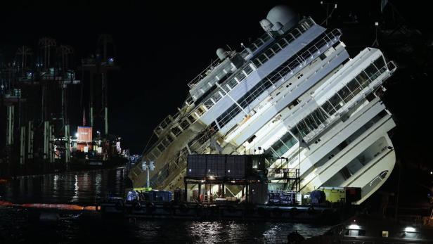 Die havarierte Costa Concordia liegt nachts auf der Seite.
