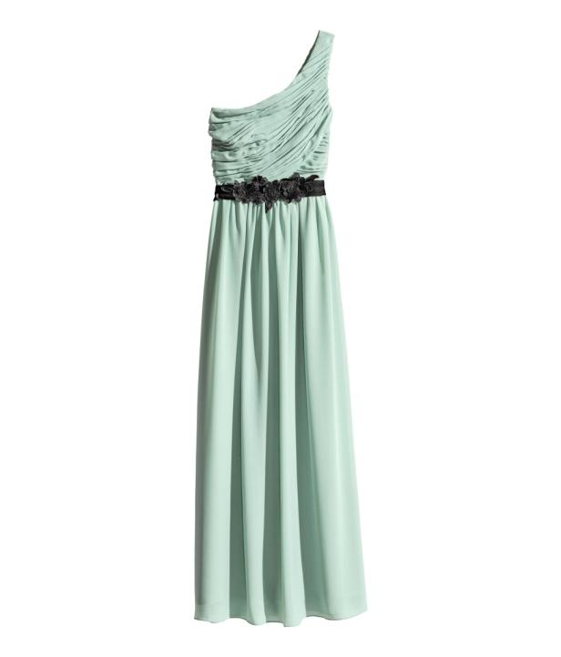 Ein mintgrünes, bodenlanges Kleid mit einer schwarzen Blumenapplikation in der Taille.