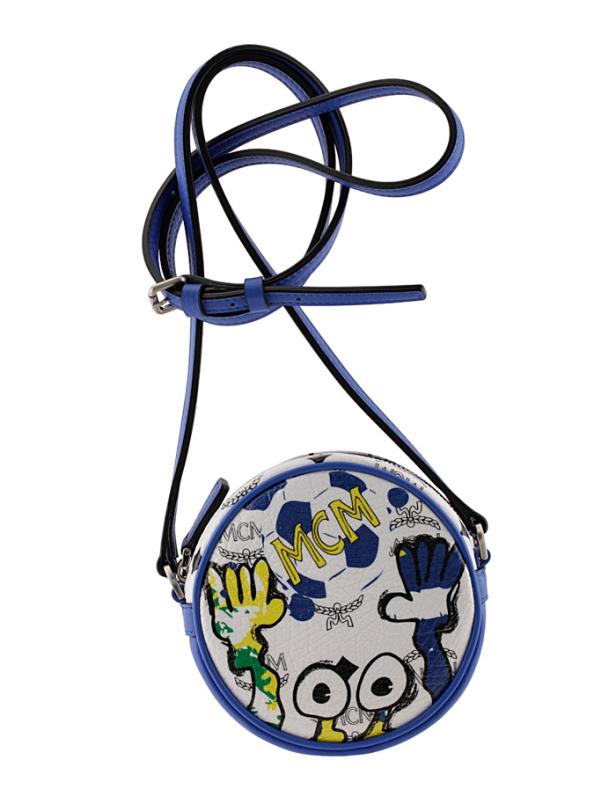 Eine runde MCM-Tasche mit Fußballmuster und blauem Riemen hängt vor einem weißen Hintergrund.