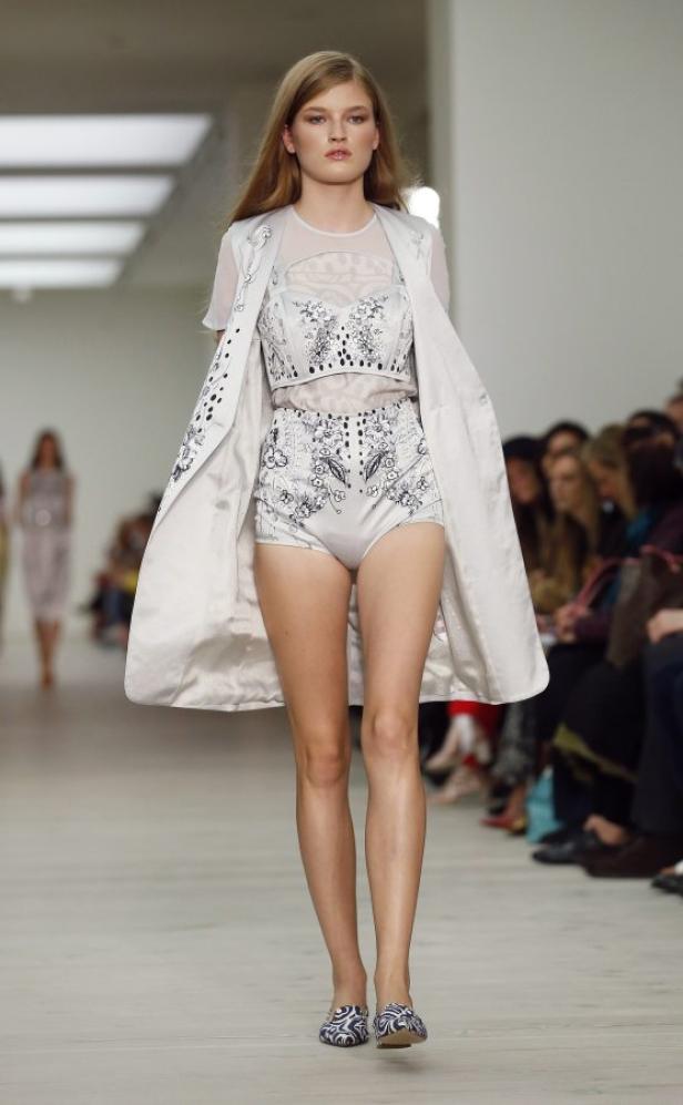 Ein Model präsentiert ein weißes Ensemble mit floralen Mustern auf dem Laufsteg.