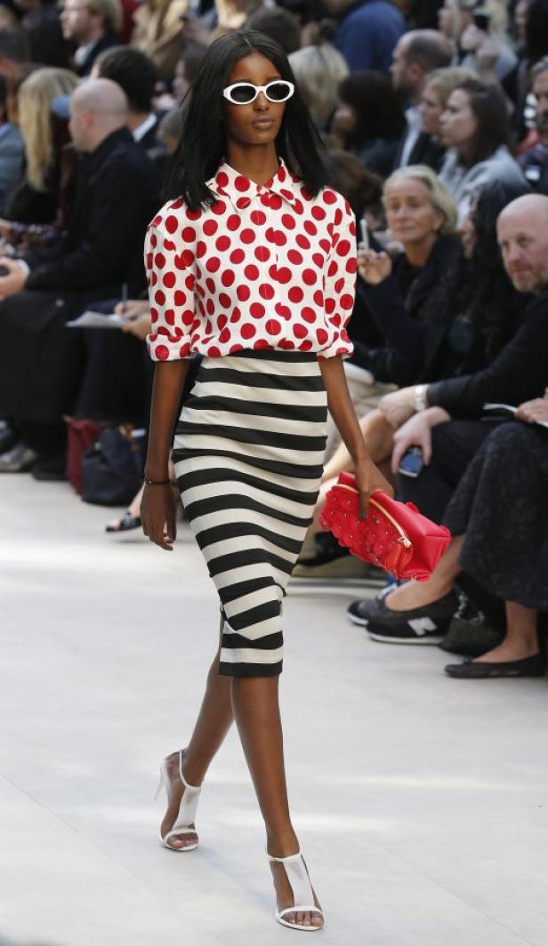 Eine Frau mit Sonnenbrille trägt ein rot-weiß gepunktetes Hemd und einen schwarz-weiß gestreiften Rock.