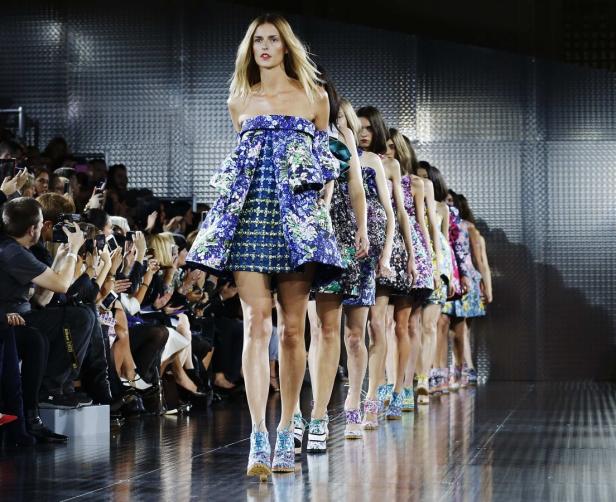 Models präsentieren farbenfrohe, blumengemusterte Kleider auf einem Laufsteg.