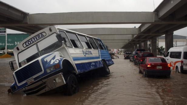 Ein Bus steckt in einer überfluteten Straße unter einer Brücke fest.