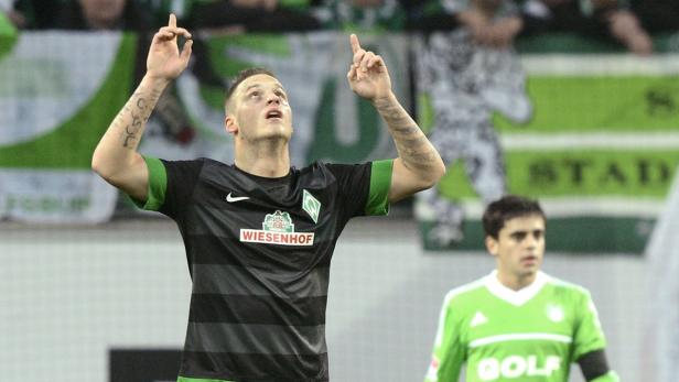 Ein Fußballspieler von Werder Bremen jubelt mit erhobenen Armen.