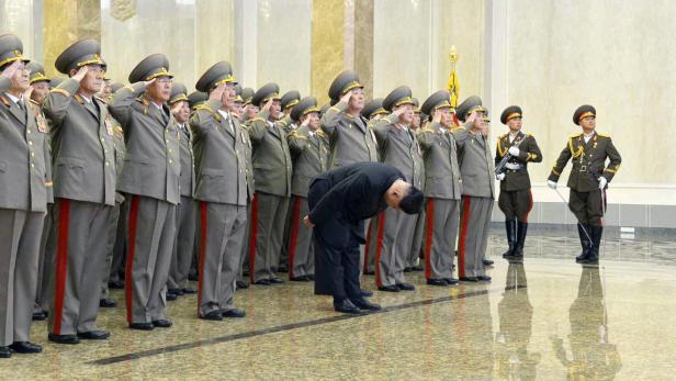 Kim Jong-un verbeugt sich vor einer Reihe salutierender nordkoreanischer Militäroffiziere.