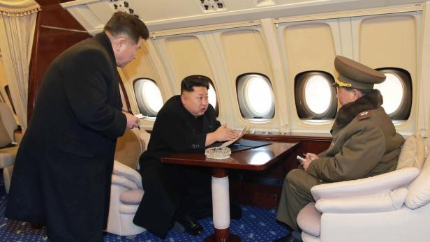 Kim Jong-un bespricht sich mit zwei Militärangehörigen in einem Flugzeug.