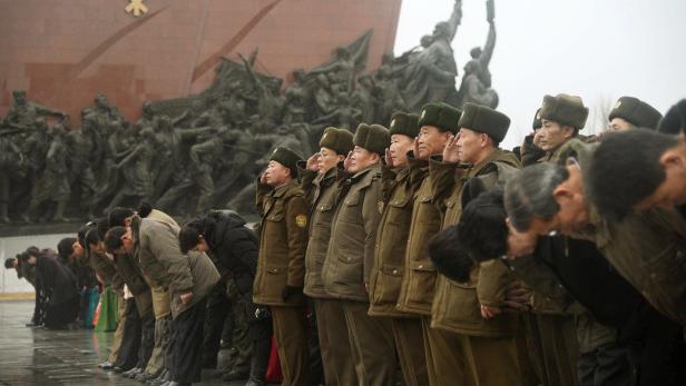 Nordkoreanische Soldaten salutieren und verbeugen sich vor einem Denkmal.