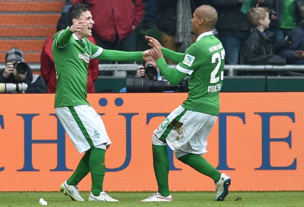 Zwei Fußballspieler von Werder Bremen feiern gemeinsam auf dem Spielfeld.