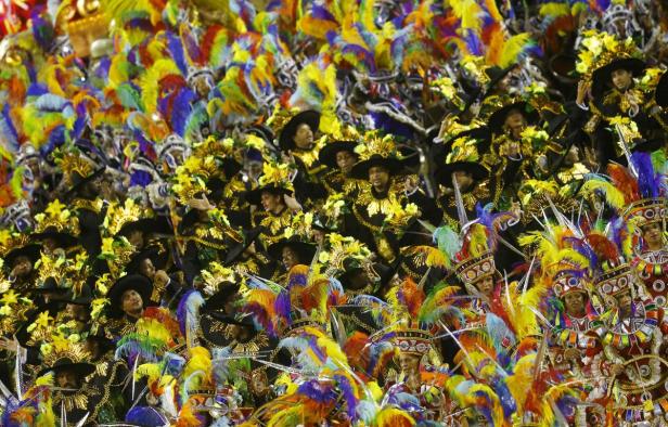 Eine farbenfrohe Parade mit vielen Menschen in aufwendigen Kostümen und Kopfbedeckungen.