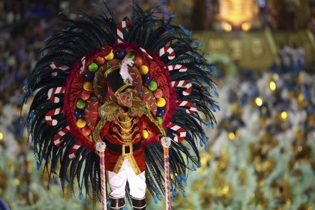 Ein Mann in einer fantasievollen, weihnachtlich inspirierten Kostümierung nimmt an einem Karnevalsumzug teil.