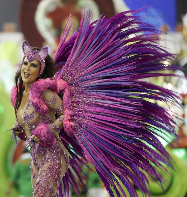 Eine Frau in einem aufwendigen, pinkfarbenen Karnevalskostüm mit großen, lila Federn.