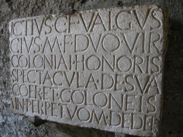 Eine Steintafel mit lateinischer Inschrift an einer Wand.